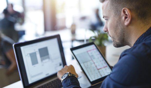 Business man looking and analyzing projects on his laptop computer and tablet.